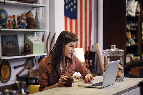 Frau benutzt Laptop, während sie am Tisch in einem Café sitzt - CAVF09601