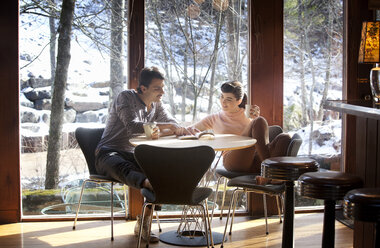 Paar, das in einem Café sitzt und ein Buch liest - CAVF09615