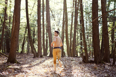 Rückansicht eines Mannes, der auf einem Feld im Wald läuft - CAVF09710
