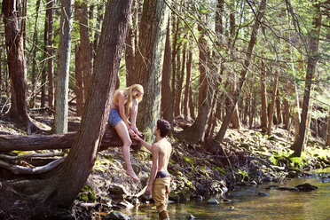 Man holding hand of girlfriend while standing in stream - CAVF09715