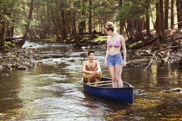 Man looking at woman standing on rowboat in river - CAVF09725