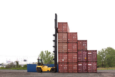 Forklift by cargo containers against clear sky - CAVF09751