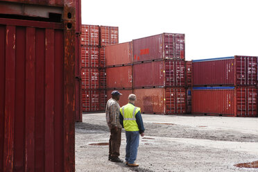 Mitarbeiter unterhalten sich bei Frachtcontainern in einem Handelsdock - CAVF09757