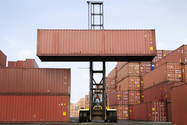 Man lifting cargo container through forklift at commercial dock - CAVF09761
