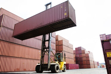 Man transporting cargo container from forklift in commercial dock - CAVF09763