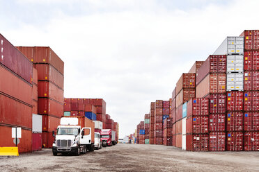 Semi-trucks on road by stack of cargo containers at commercial dock - CAVF09771