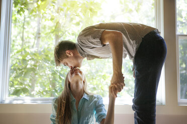 Man kissing woman forehead by window at home - CAVF09905