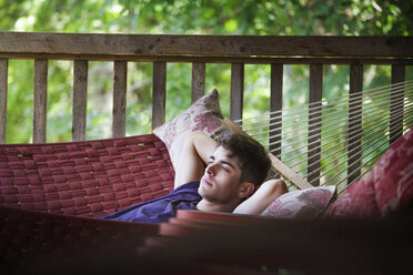 Nachdenklicher Mann entspannt sich auf einer Hängematte am Geländer zu Hause - CAVF09916