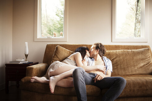 Couple kissing while relaxing on sofa - CAVF09966