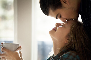 Mann küsst Freundin zu Hause auf die Stirn - CAVF10027