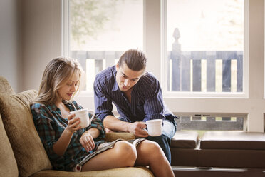 Couple reading magazine while drinking coffee at home - CAVF10028