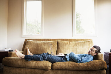 Man sleeping on sofa at home - CAVF10041
