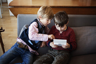 Hoher Blickwinkel von Geschwistern, die ein Videospiel spielen, während sie zu Hause auf dem Sofa sitzen - CAVF10092