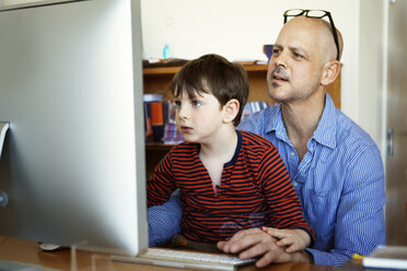 Vater und Sohn benutzen einen Desktop-Computer zu Hause - CAVF10103