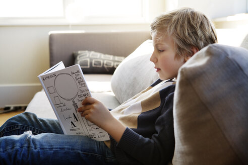 Junge beim Lernen auf dem Sofa zu Hause sitzend - CAVF10112