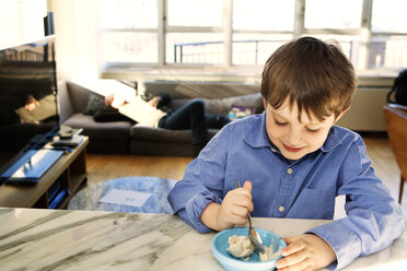 Glücklicher Junge isst Eis in einer Schüssel zu Hause - CAVF10115