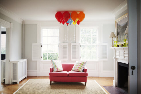 Helium balloons over sofa in living room at home - CAVF10120