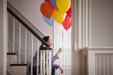 Frau sitzt auf einer Treppe und hält Heliumballons - CAVF10142