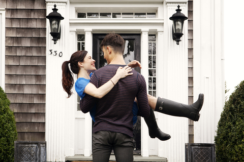 Mann trägt Frau, während er im Hinterhof steht, lizenzfreies Stockfoto