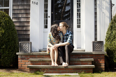 Couple kissing while on sitting steps at front stoop - CAVF10201