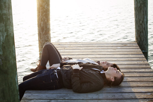 Paar auf dem Pier liegend gegen den See bei Sonnenuntergang - CAVF10212