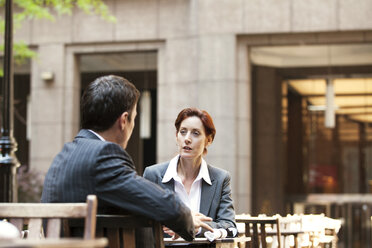 Geschäftsmann und Geschäftsfrau, die in einem Straßencafé sitzen und diskutieren - CAVF10220