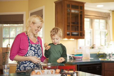 Glückliche Mutter und Sohn bei der Zubereitung von Essen in der Küche zu Hause, lizenzfreies Stockfoto