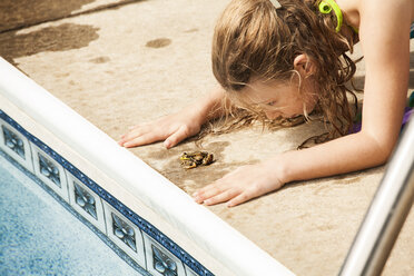 Mädchen spielt mit Frosch am Pool - CAVF10332