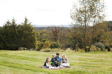 Familie genießt Picknick auf einer Wiese - CAVF10335