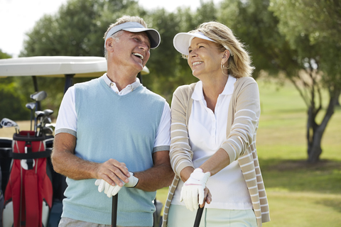 Lachendes Seniorenpaar auf dem Golfplatz, lizenzfreies Stockfoto