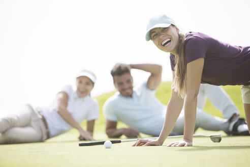 Freunde liegen und lachen auf dem Golfplatz - CAIF19497