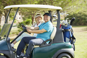 Seniorenpaar fährt Golfwagen auf dem Golfplatz - CAIF19515