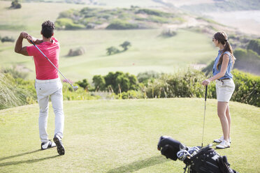 Couple teeing off on golf course - CAIF19517