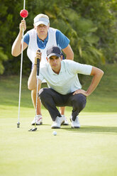 Caddy und Golfer auf dem Putting Green - CAIF19518