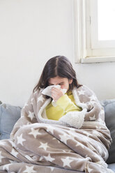 Erkältetes Mädchen, das zu Hause auf der Couch sitzt und sich die Nase putzt - LVF06789
