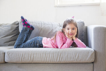 Porträt eines lächelnden kleinen Mädchens, das auf der Couch liegt - LVF06792