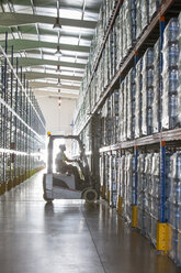 Worker operating forklift in warehouse - CAIF19582