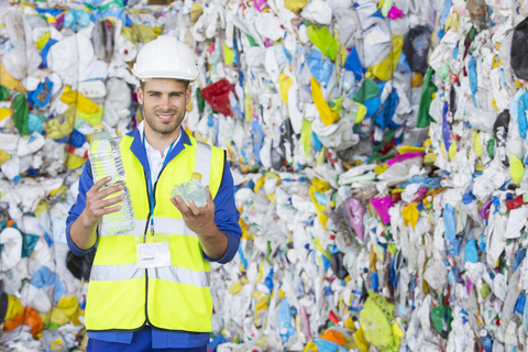Arbeiter hält eine gepresste Plastikflasche im Recyclingzentrum, lizenzfreies Stockfoto