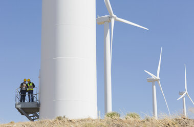 Arbeiter sprechen über eine Windkraftanlage in ländlicher Umgebung - CAIF19635