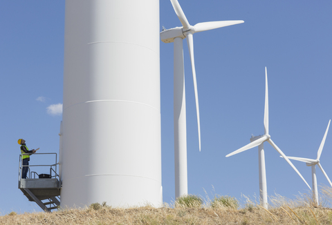 Arbeiter begutachtet Windkraftanlage in ländlicher Umgebung, lizenzfreies Stockfoto