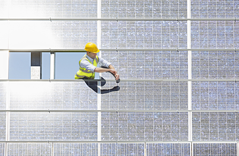 Arbeiter bei der Untersuchung eines Solarpanels in einer ländlichen Umgebung, lizenzfreies Stockfoto