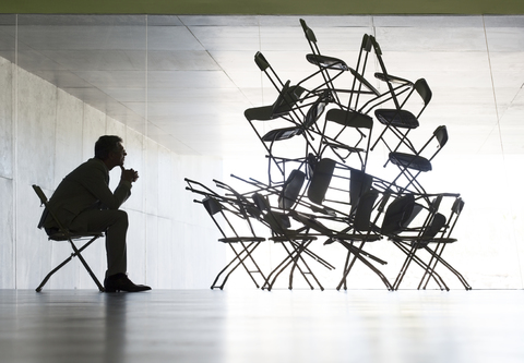 Geschäftsmann betrachtet Bürostuhl Installation Kunst, lizenzfreies Stockfoto