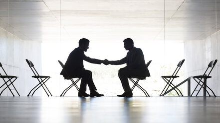 Businessmen shaking hands in office - CAIF19671