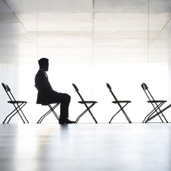 Silhouette eines Geschäftsmannes, der im Büro sitzt - CAIF19690