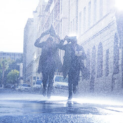 Geschäftsleute bedecken ihre Köpfe mit Zeitungen im Regen - CAIF19708