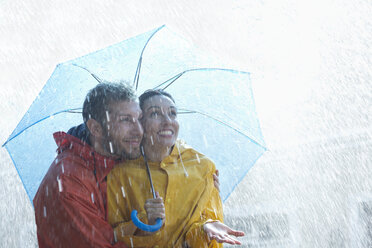 Glückliches Paar unter Regenschirm im Regen - CAIF19726