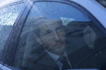 Close up of businessman in car looking up at rain - CAIF19730