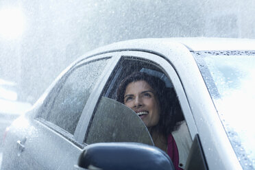 Smiling businesswoman in car looking up at rain - CAIF19737