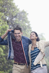 Happy couple walking in rain - CAIF19763