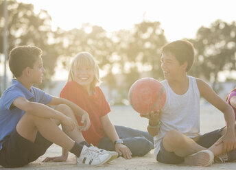 Children sitting with soccer ball outdoors - CAIF19794